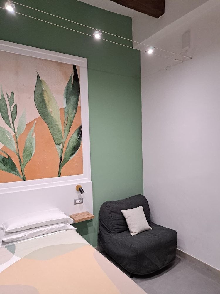 Hotelzimmer mit Wandbild, grüne Akzentwand und dunklem Polstersessel.