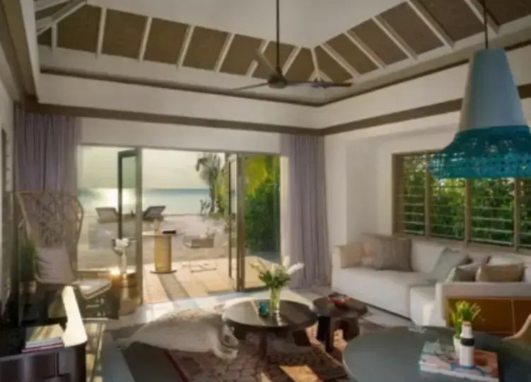 Wohnbereich mit geöffneter Verandatür und direktem Blick auf den Strand und das Meer.