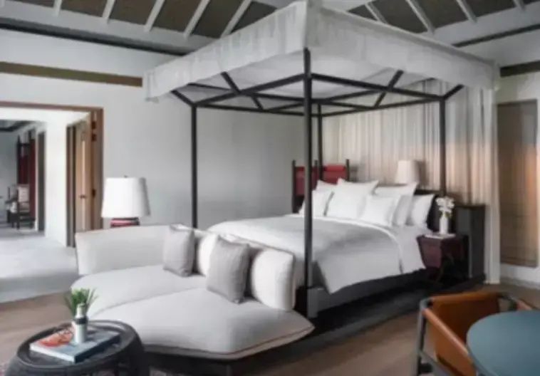 Schlafbereich mit großem Himmelbett in Weiß und angeschlossenem hellen Sitzbereich.