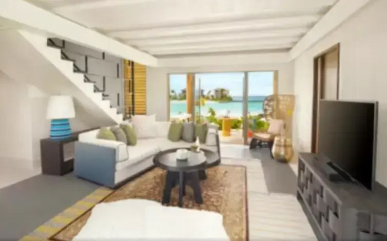 Helles Wohnzimmer mit gemütlicher Eckcouch und freiem Blick auf den Strand.