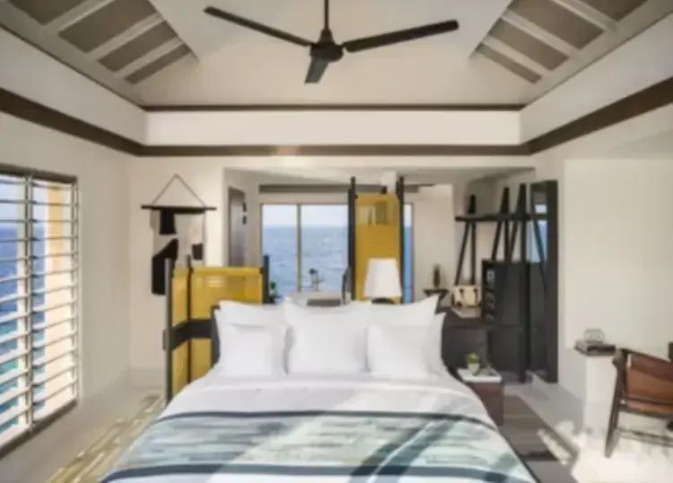 Schlafbereich einer Überwasservilla mit großem Doppelbett und Blick auf das Meer