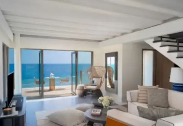 Heller Wohnbereich einer Villa mit Sitzecke und Blick auf das blaue Meer