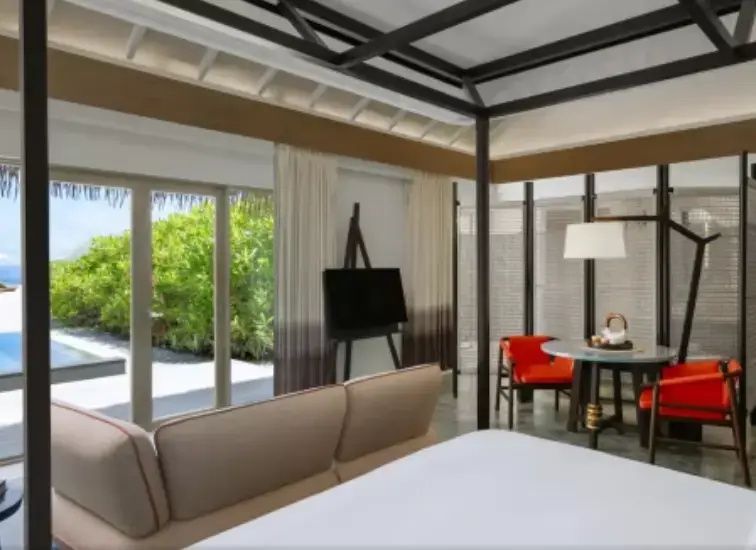 Wohnbereich und Schlafbereich einer Villa mit Doppelbett, Sofa und Fernseher.