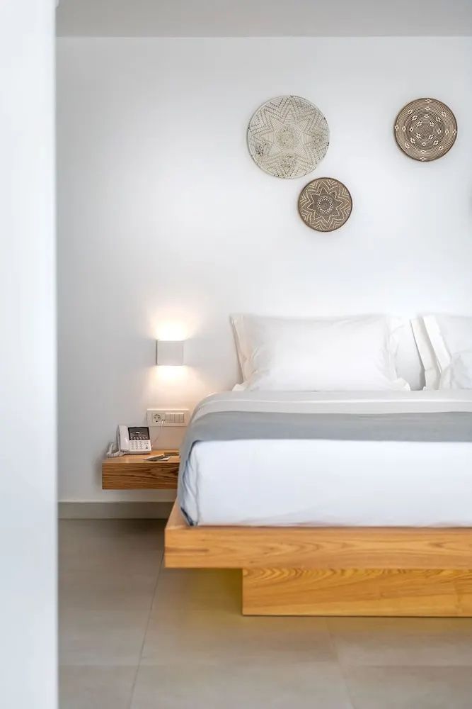 Doppelbett mit weißer Bettwäsche, schwimmendem Nachttisch aus Holz und Wanddekoration.