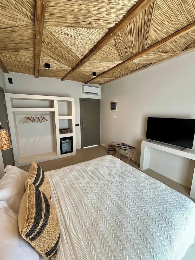 Blick vom Bett auf einen offenen Kleiderschrank, Minibar und Fernseher im Zimmer.