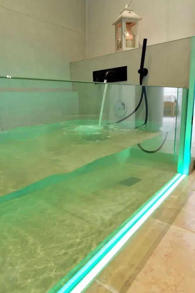 Einlassender Whirlpool mit Glasfront und grüner Unterwasserbeleuchtung im Innenraum.