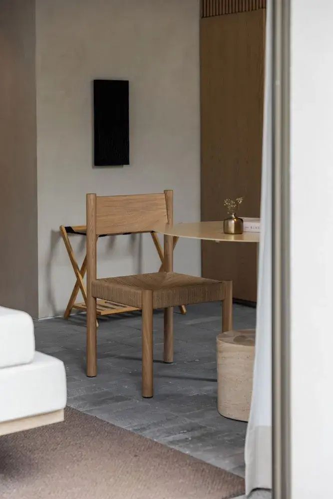 Holzstuhl mit geflochtener Sitzfläche an einem Tisch im Hotelzimmer.
