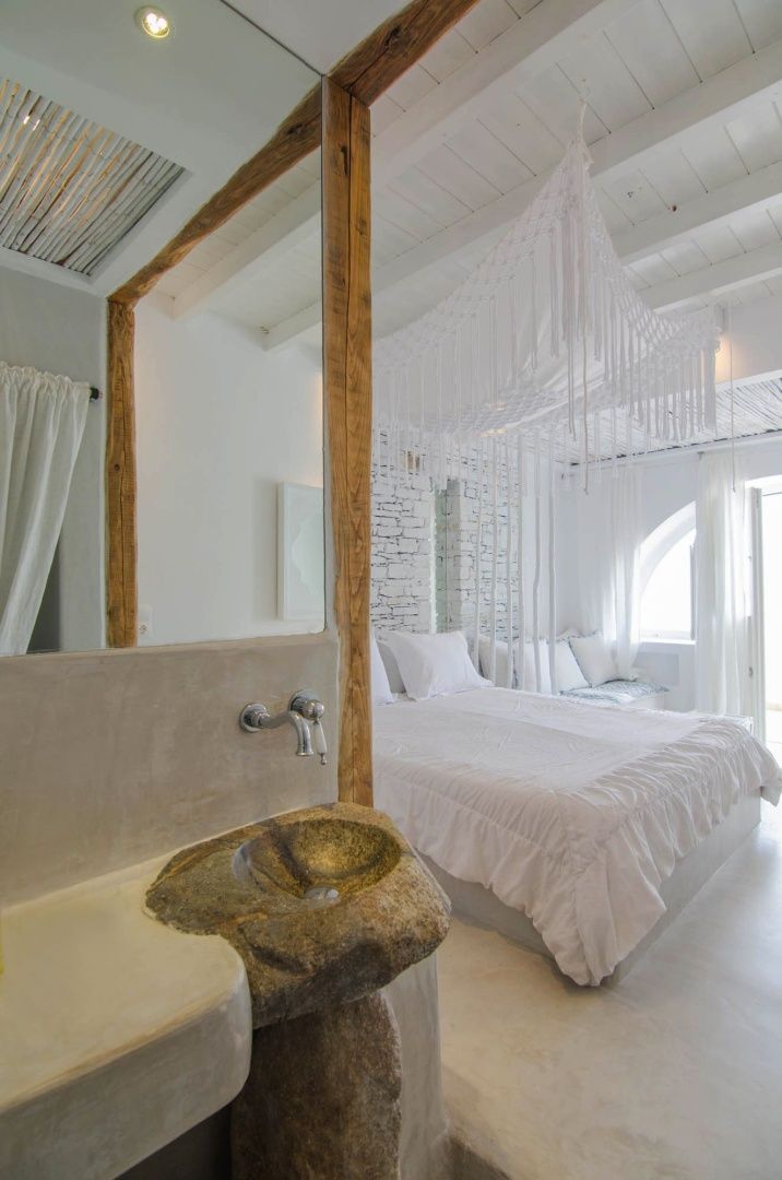 Offener Wohnbereich mit einem Steinwaschbecken im Vordergrund und Bett im Hintergrund.