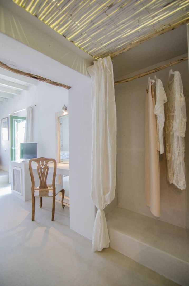 Schminktisch aus Holz und offener Garderobenbereich in einem weiß gestalteten Hotelzimmer.