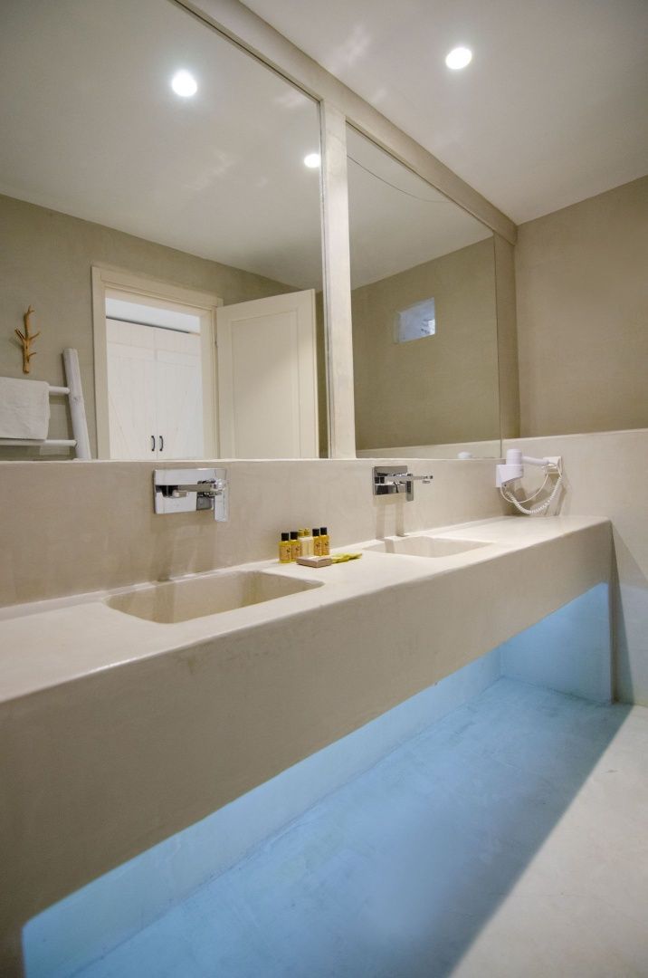 Modernes Badezimmer mit breitem Doppelwaschbecken aus hellem Stein und großem Spiegel.