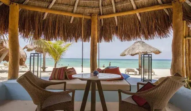 Überdachte Terrasse mit Sitzgelegenheiten und direktem Blick auf den Sandstrand und das Meer.