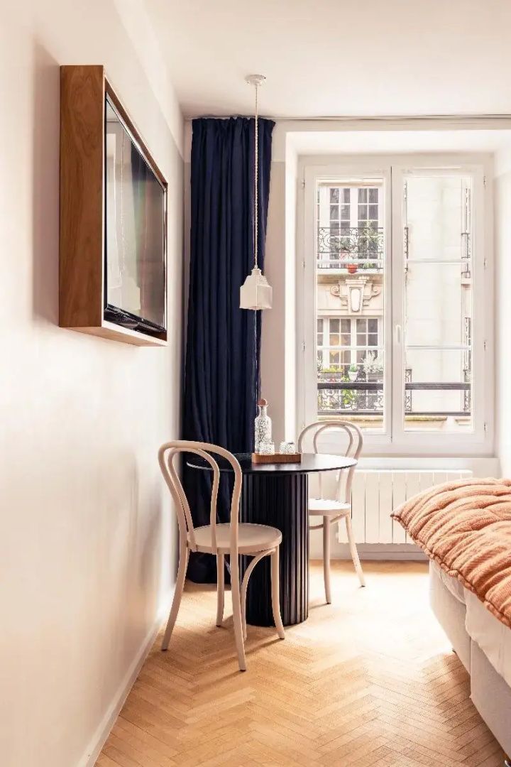 Sitzbereich im Zimmer mit rundem Tisch, zwei Stühlen und Blick aus dem Fenster.