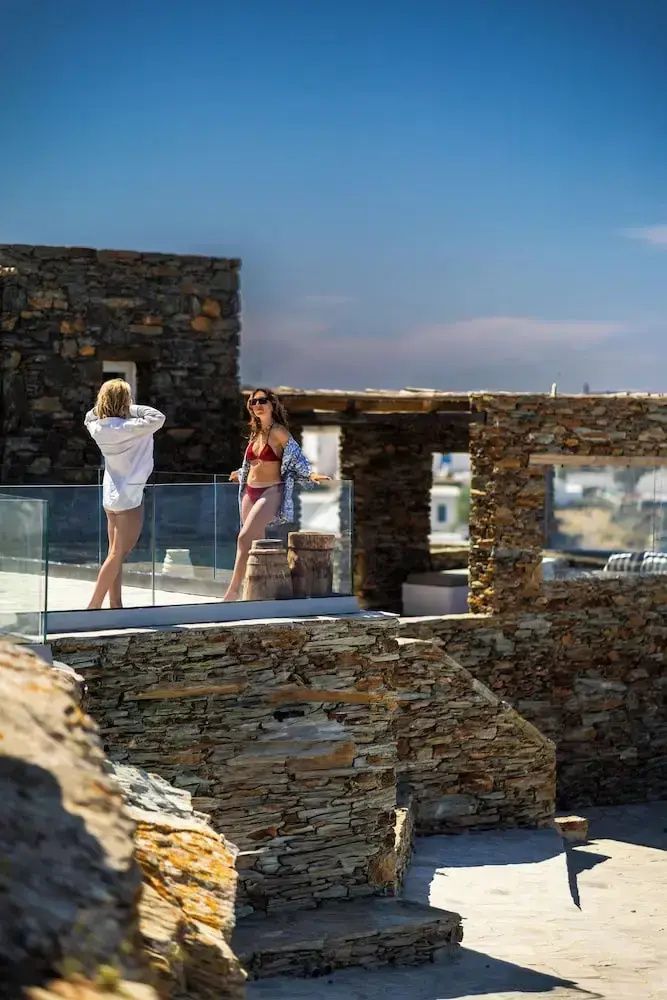 Zwei Personen stehen auf einer traditionellen Terrasse aus Naturstein mit Glasgeländer.