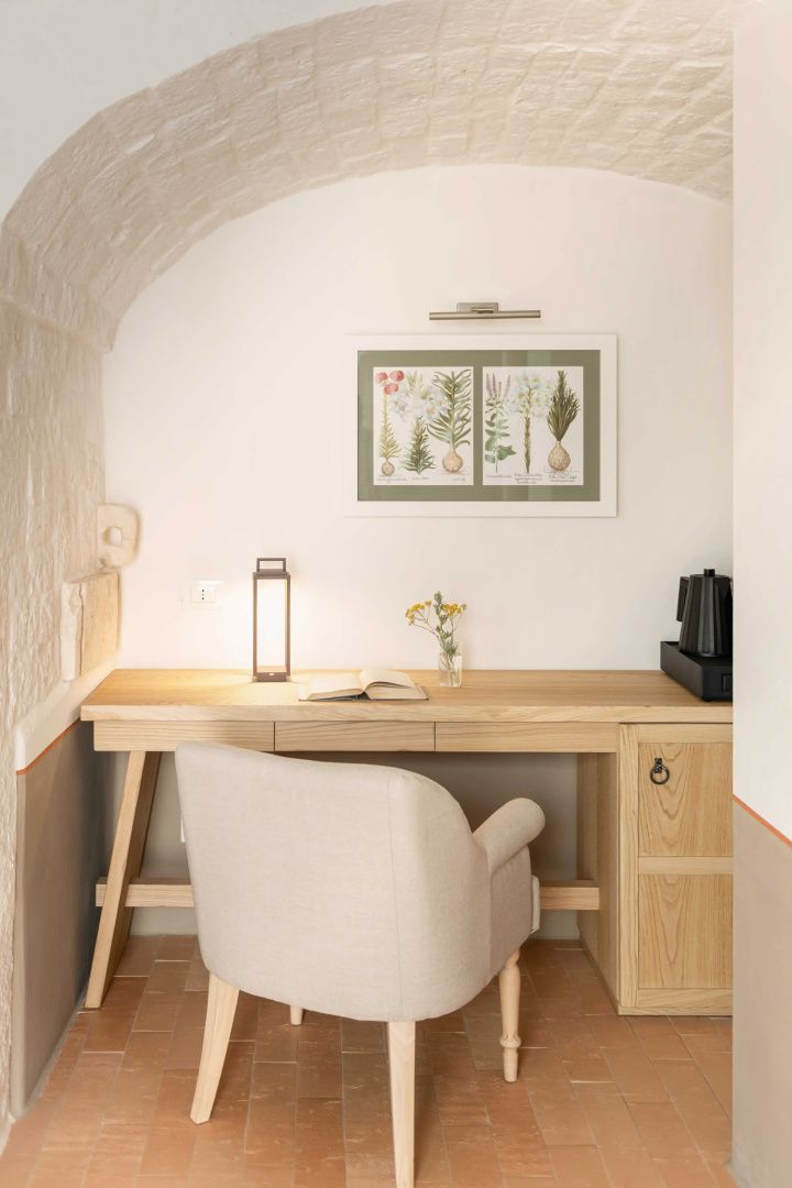 Arbeitsplatz mit Holzschreibtisch, gepolstertem Stuhl und Tischleuchte im Zimmer.