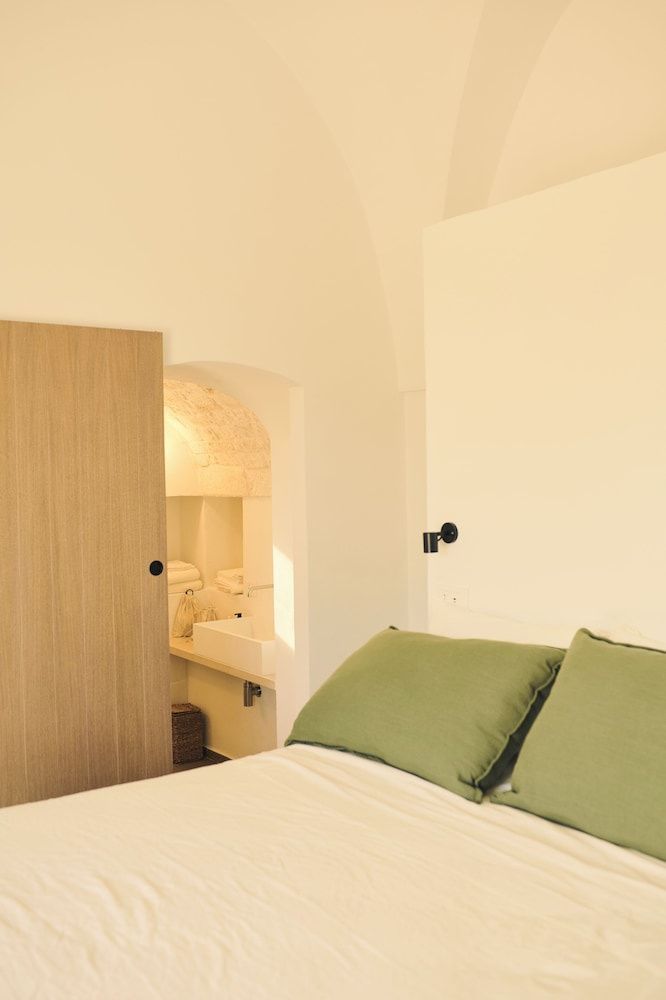 Blick vom Doppelbett auf eine Schiebetür aus Holz und das Badezimmer.