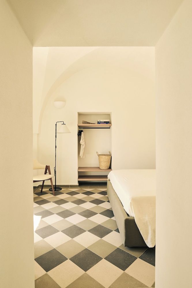 Einblick in ein helles Zimmer mit gemusterten Fliesen, Stehleuchte und einer offenen Wandnische.