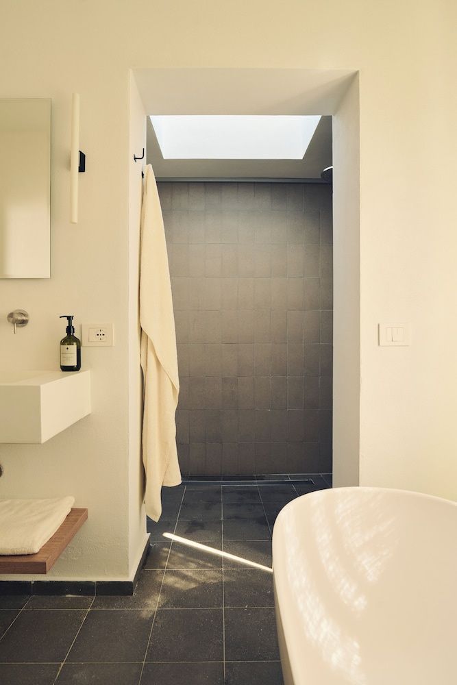 Badezimmerbereich mit weißem Waschbecken, aufgehängtem Handtuch und Dusche mit Dachfenster.