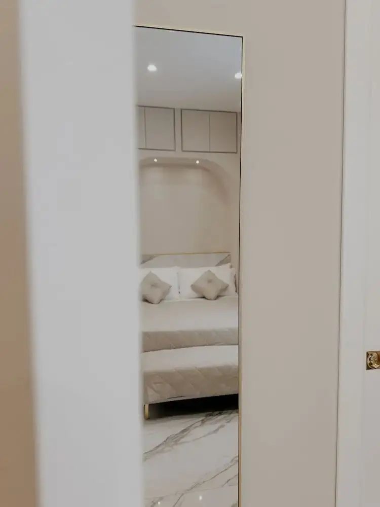 Blick durch den Türrahmen auf ein Doppelbett mit hellen Kissen und einer Fußbank.