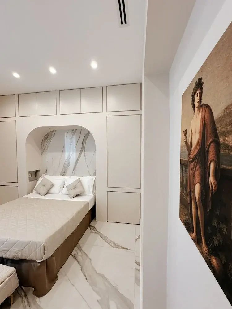 Schlafbereich mit Doppelbett in einer Wandnische mit Marmormuster und einem Kunstwerk an der Wand.