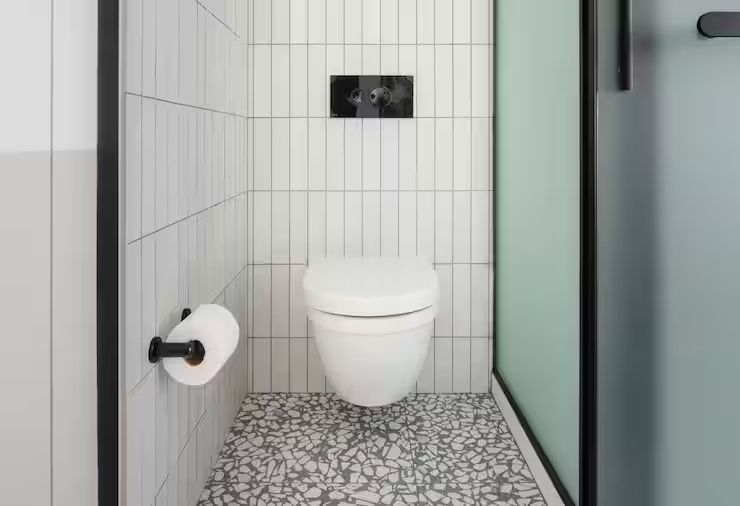 Modernes WC mit weißen Wandfliesen, Terrazzoboden und schwarzer Betätigungsplatte