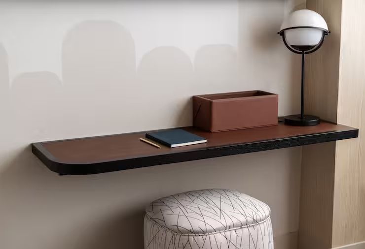 Schreibtisch aus Holz mit einem Notizbuch, Stift und einem Hocker im Zimmer