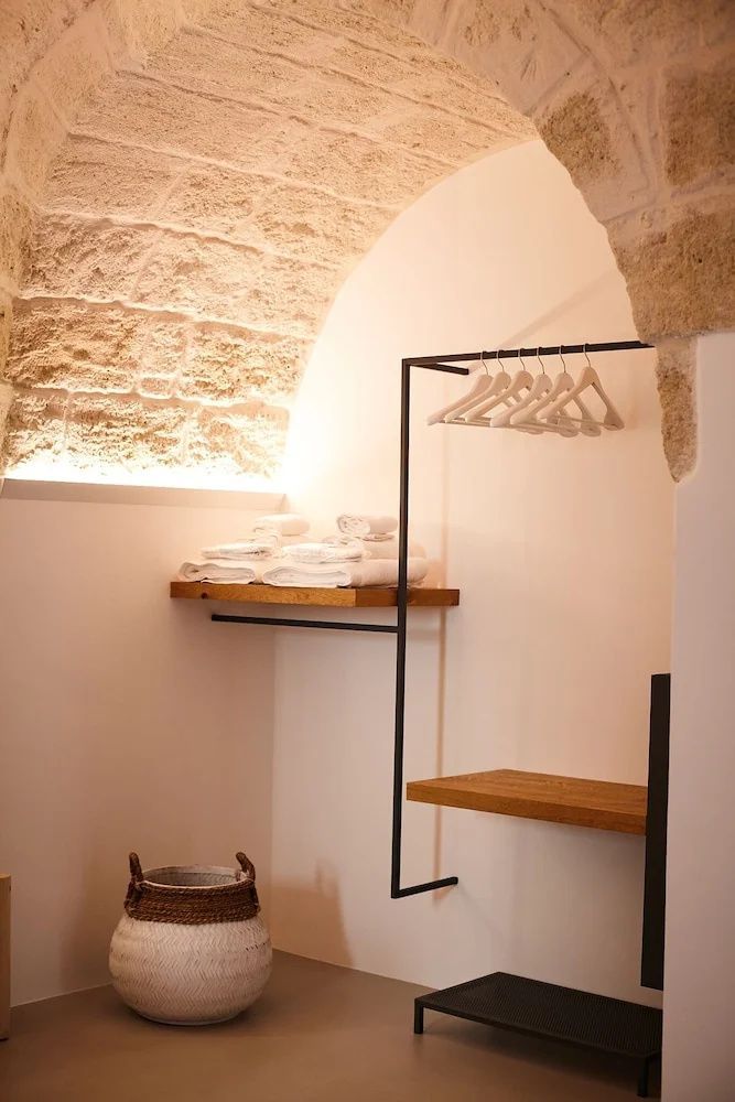 Offene Garderobe aus schwarzem Metall unter einer Decke aus Naturstein.