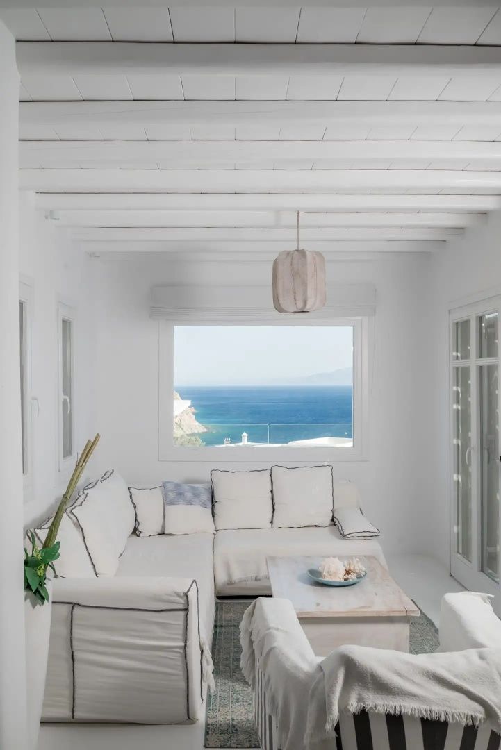 Heller Raum mit weißem Sofa und freiem Blick durch das Fenster auf das blaue Meer.