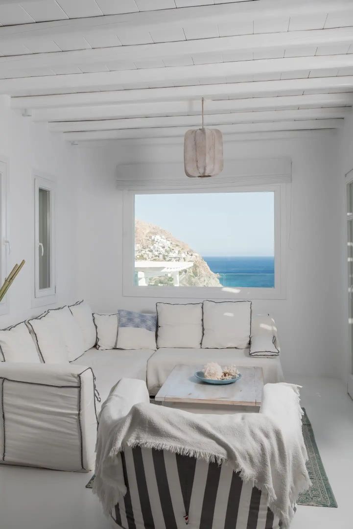 Weiß eingerichteter Wohnbereich mit großem Fenster und Blick auf das Meer