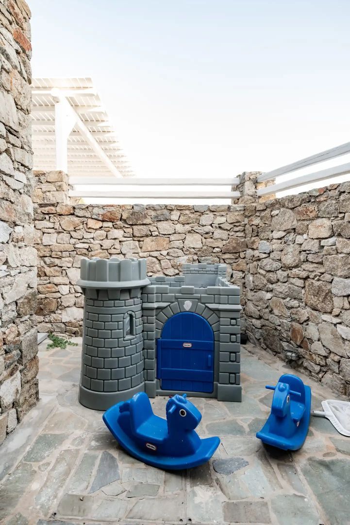 Ein Kinderspielbereich auf einer gepflasterten Terrasse mit einer kleinen Kunststoffburg.