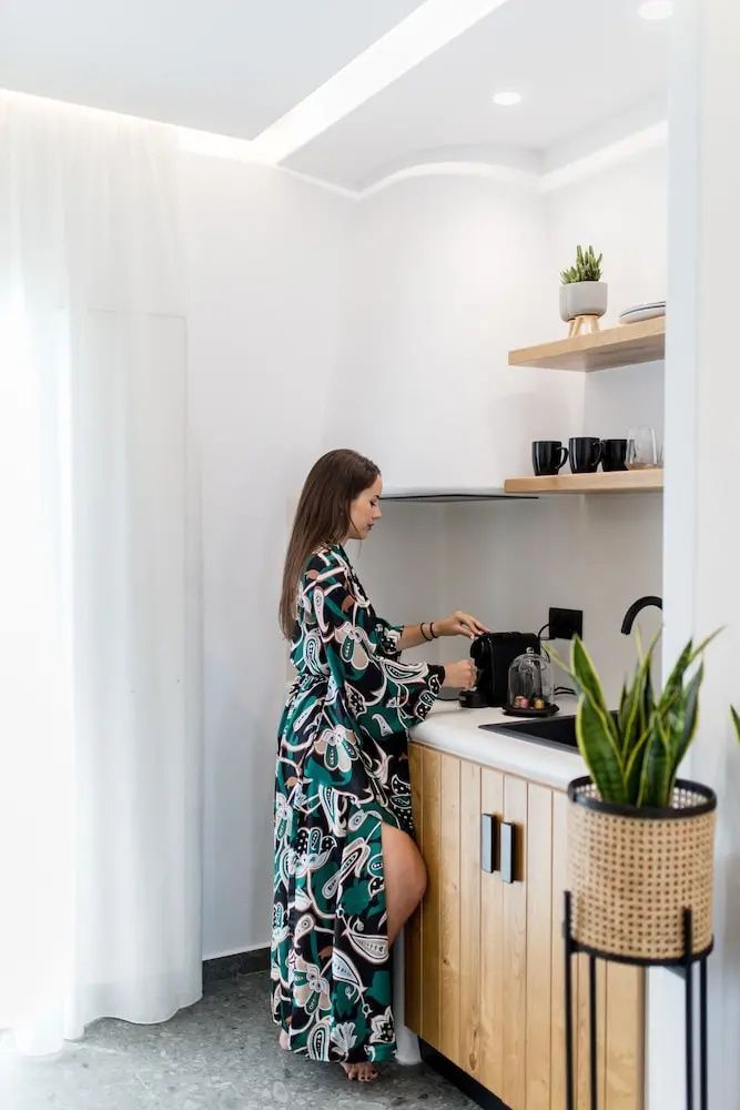 Eine Frau in einem gemusterten Mantel bedient eine Kaffeemaschine in der Küchenzeile.