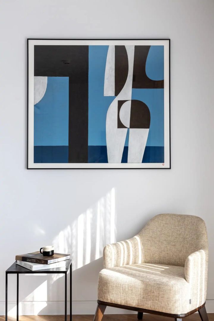 Abstrakte Kunst an der Wand über einem Sessel und Beistelltisch.
