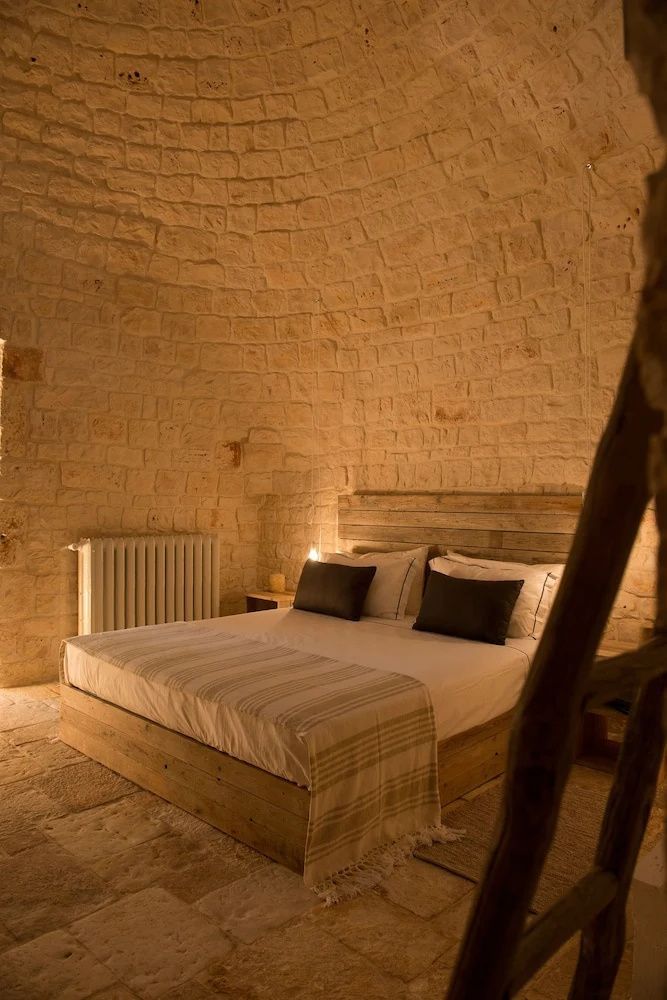 Ein gemachtes Doppelbett steht in einem Schlafzimmer mit gewölbter Steinwand und Heizkörper.