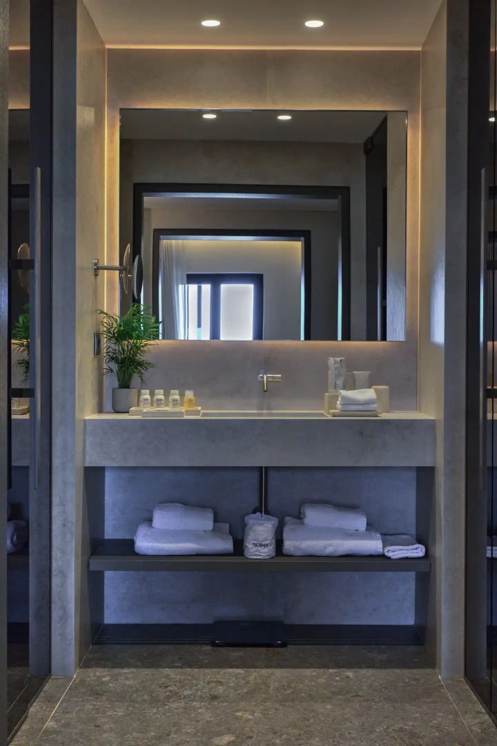 Badezimmer mit beleuchtetem Spiegel, großem Waschtisch und abgelegten Handtüchern.