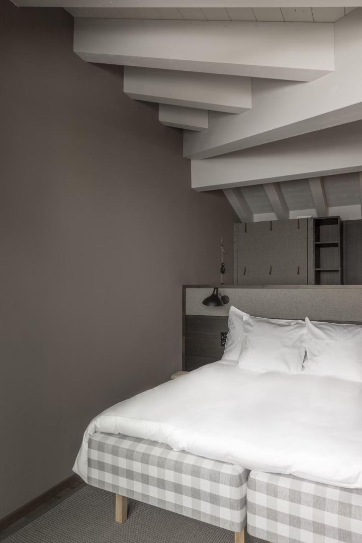 Doppelbett mit weißer Bettwäsche unter einer schrägen Decke mit hellen Holzbalken.