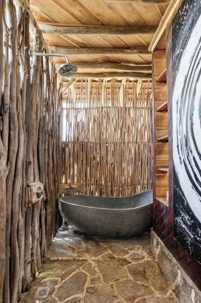 Badezimmer mit stehender Badewanne, Regendusche und Wänden aus naturbelassenem Holz.