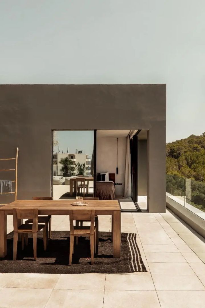Terrasse einer Suite mit Holztisch, Stühlen und angrenzender Vegetation am Hügel.