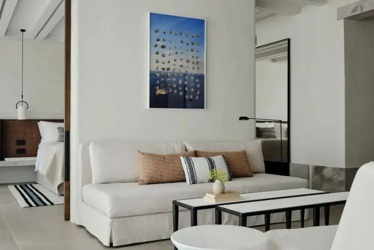 Helles Sofa mit Kissen und Couchtisch in einem minimalistisch gestalteten Hotelzimmer