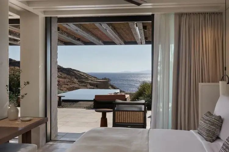 Terrasse mit Privatpool und Sitzgelegenheiten hinter der geöffneten Tür des Zimmers.