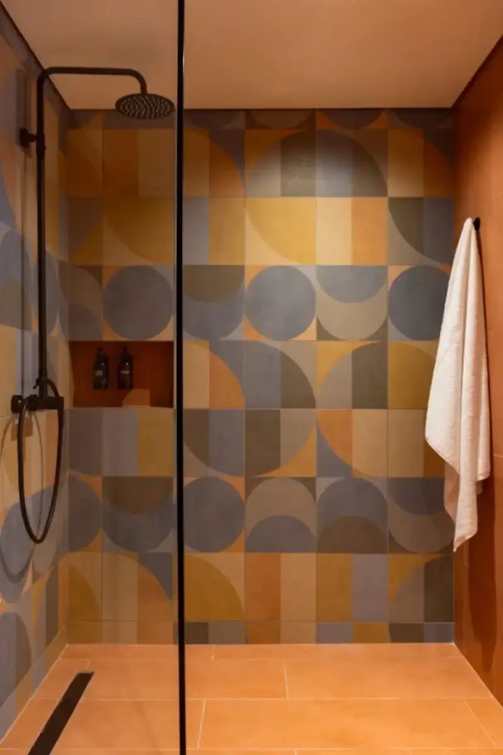 Dusche mit bunt gemusterten Fliesen und schwarzer Duscharmatur im Badezimmer
