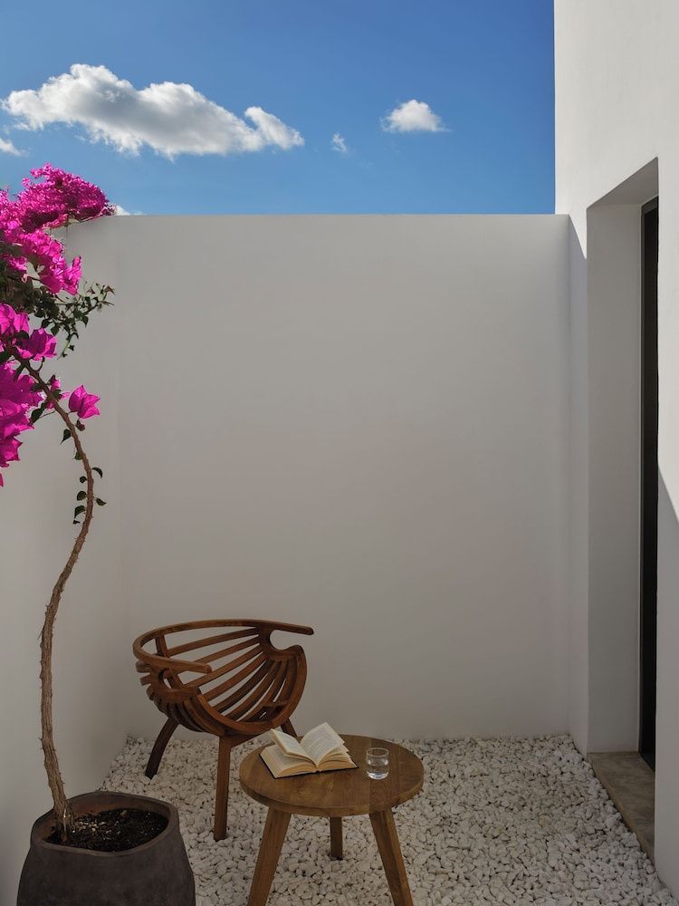 Sitzbereich auf einer Terrasse mit Holzstuhl, Beistelltisch und Bougainvillea.