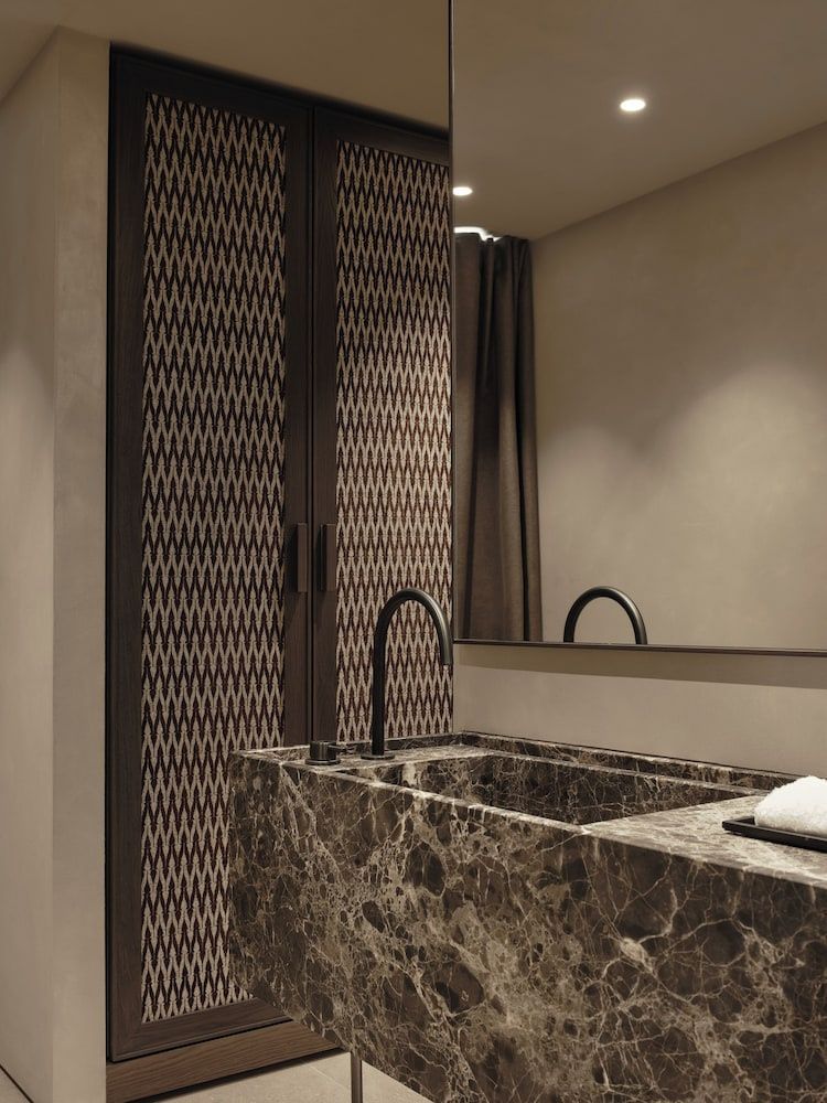 Badezimmer mit einem Waschtisch aus dunklem Stein und schwarzer Armatur.