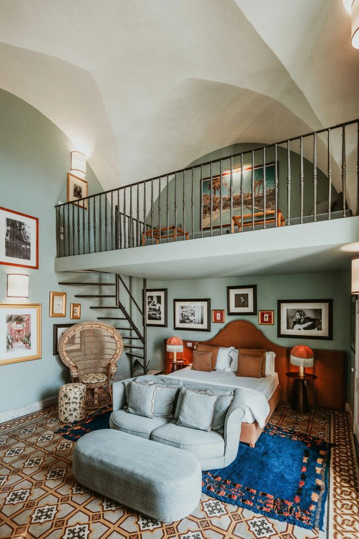 Zweistöckiges Hotelzimmer mit Doppelbett, Sofa, Wendeltreppe und Empore unter einem Gewölbe.