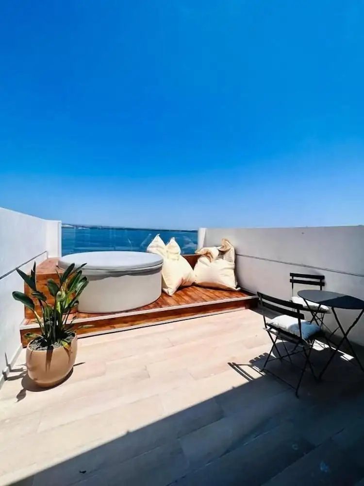 Dachterrasse mit einem Whirlpool, Sitzkissen und Tischchen mit Blick auf das Meer.