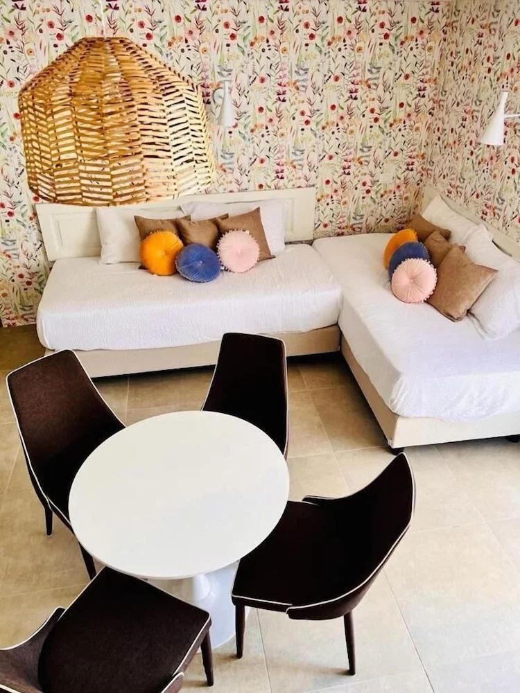 Sitzbereich im Zimmer mit weißem Sofa, bunten Kissen und rundem Tisch mit Stühlen.