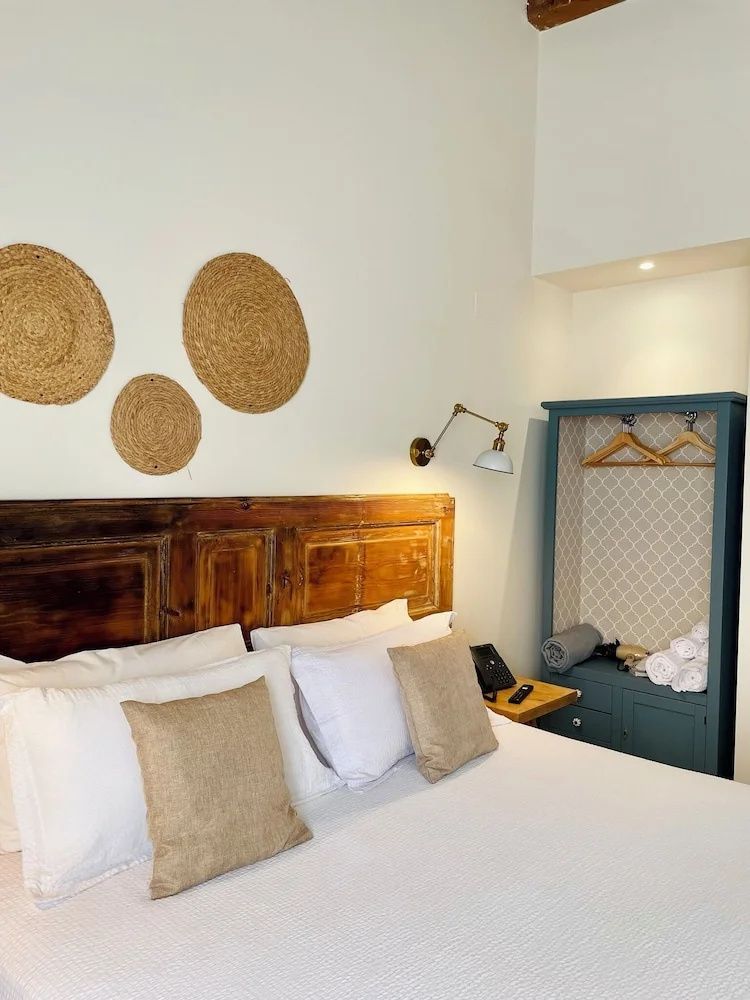 Helles Doppelbett mit Holzkopfteil, Wanddeko aus Geflecht und blauem Schrank.