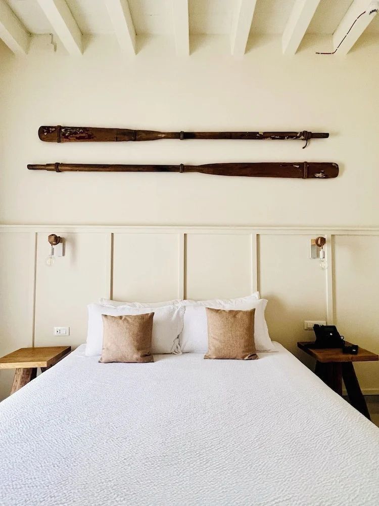 Doppelbett mit braunen Kissen und zwei dekorativen Holzrudern an der Wand.