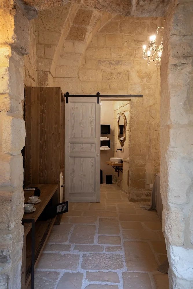Blick durch ein Zimmer mit Steinwänden auf eine Schiebetür zum Badezimmer.