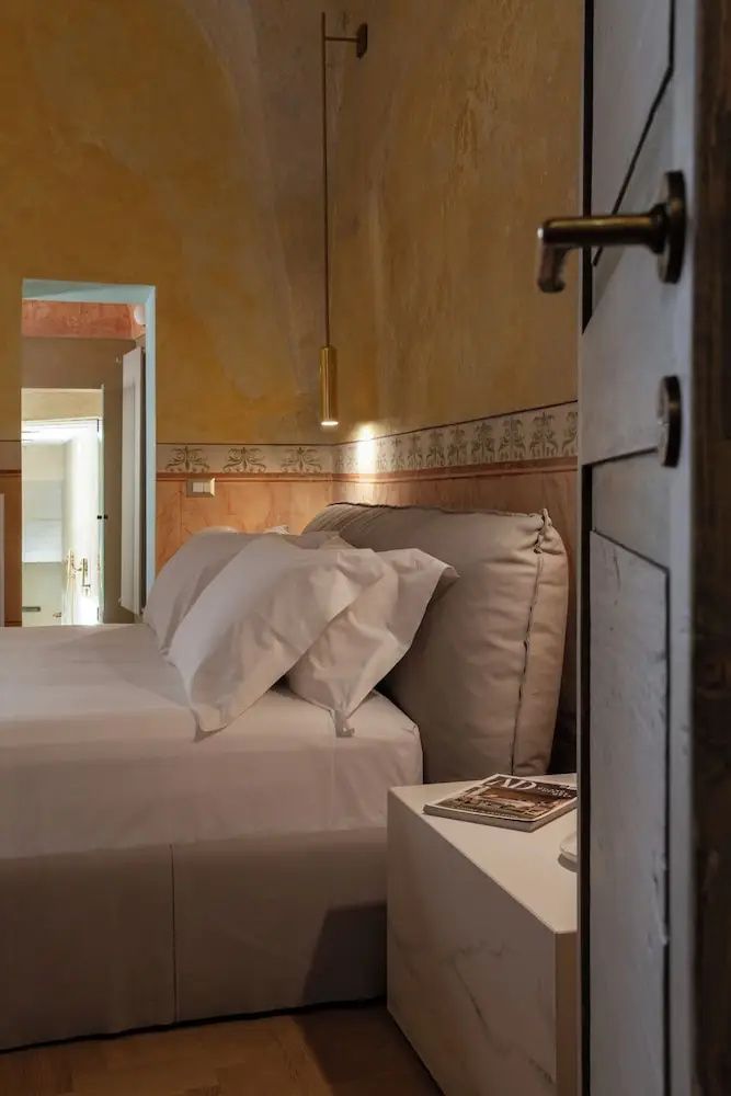 Blick in ein geräumiges Hotelzimmer mit Doppelbett, Beistelltisch und angrenzendem Raum