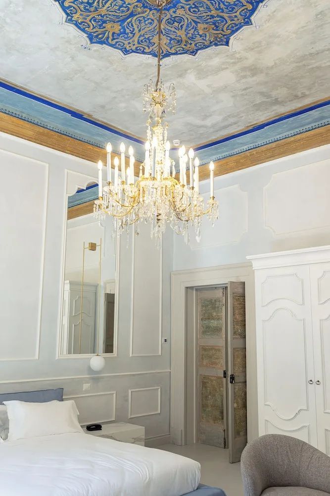 Hohes Hotelzimmer mit einem Kristallkronleuchter, verzierten Deckenleisten und weißem Schrank.