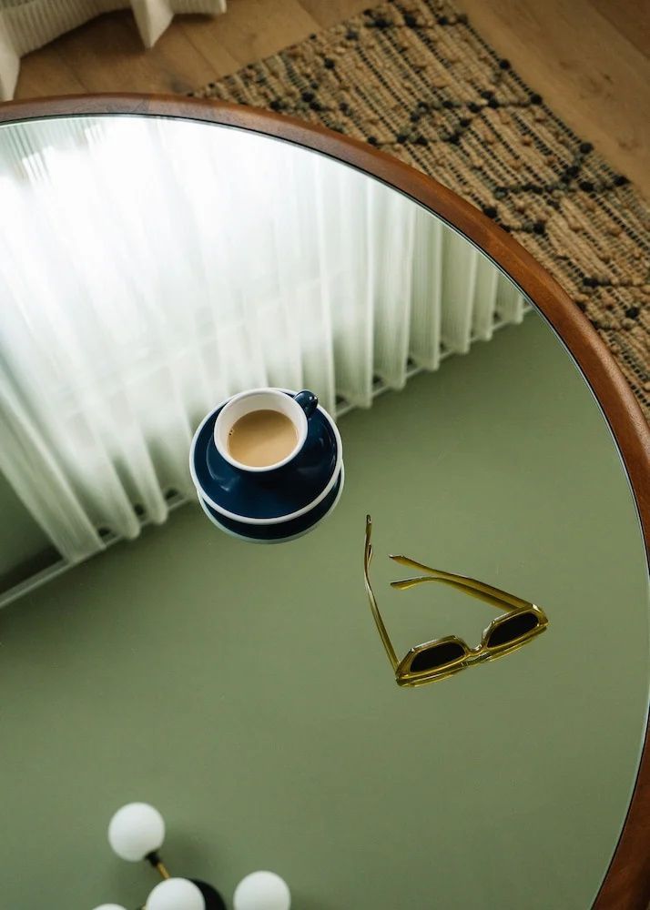 Nahaufnahme eines runden Tischs mit einer blauen Kaffeetasse und einer Sonnenbrille.